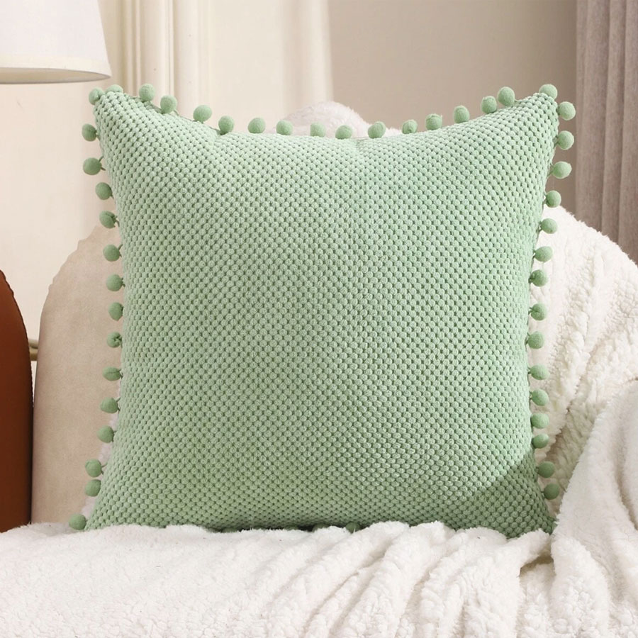 Yesrentals-Kussen-groen-met-pompoms Dit kussen eva groen is een tof kussen met een stippen patroon
